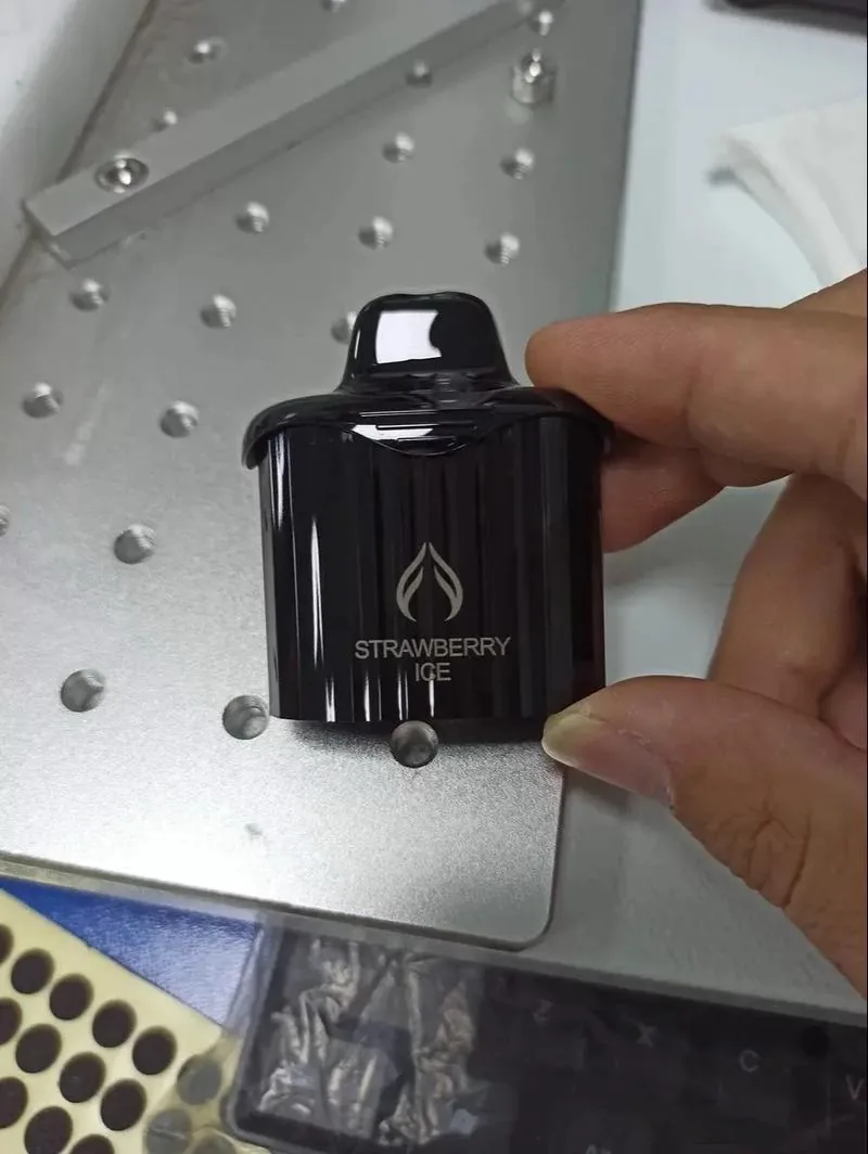 Laser-marked black plastic consumer component with a light-contrast mark on a dark surface.
