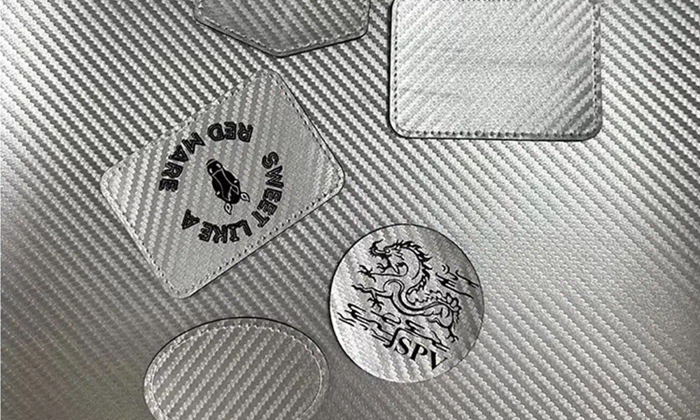 Laser-marked graphics on woven carbon-fiber composite pieces