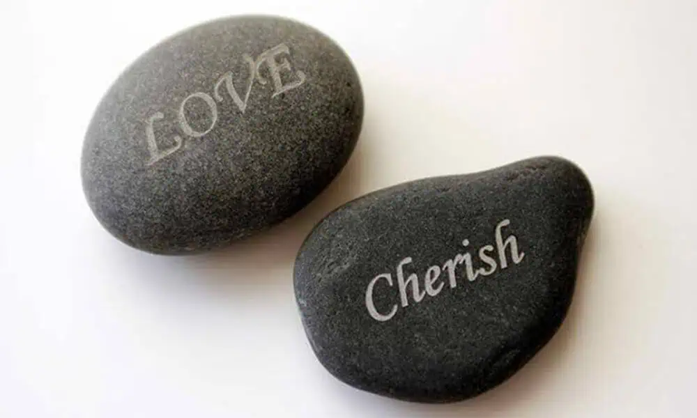 Laser-marked stone sample with light text on a dark mineral surface