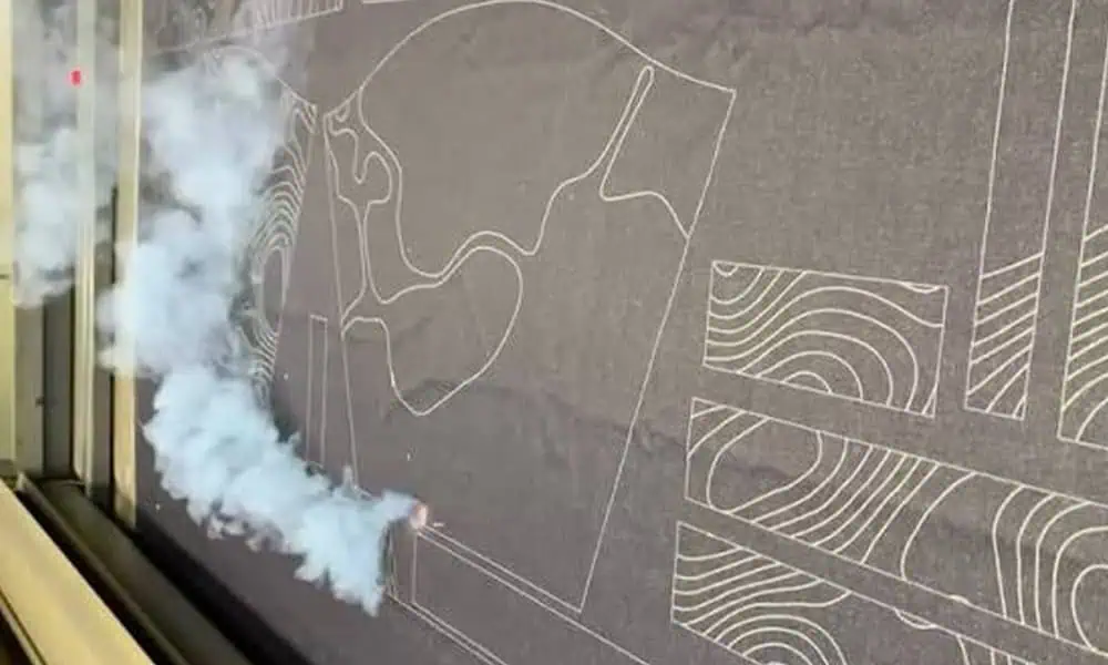 Laser processing a textile surface with visible smoke at the marking area
